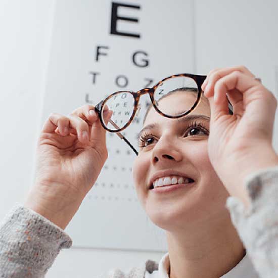 Frau mit Brille vor Sehtafel.